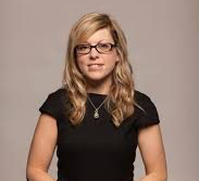 An image of Suzi rees wearing a black formal dress with short sleeves. Suzi has her long blonde hair down and she is wearing glasses.